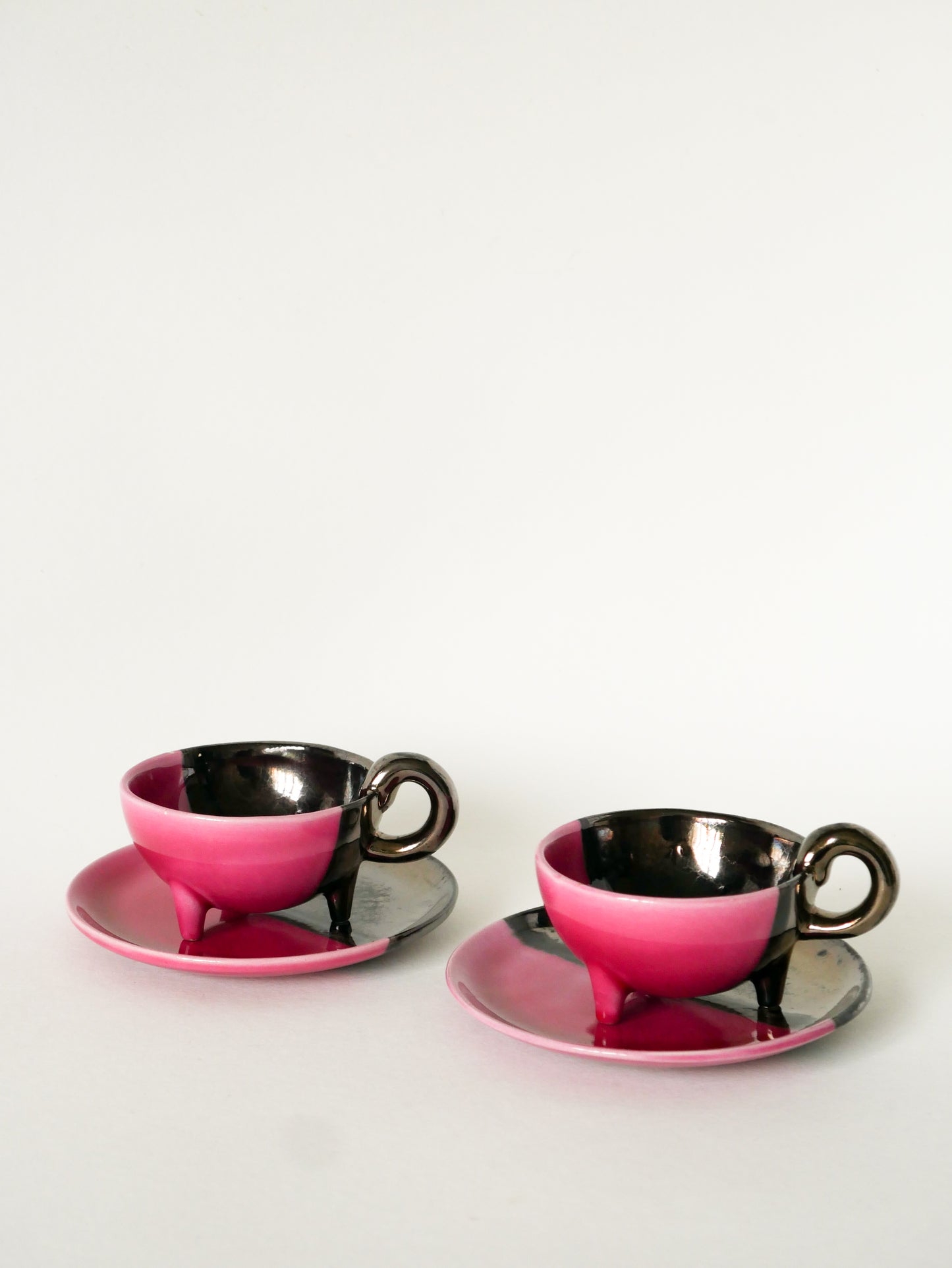 Duo de tasses tripodes et soucoupes Vallauris en céramique bicolore, Rose et Noir Irisé, 1970