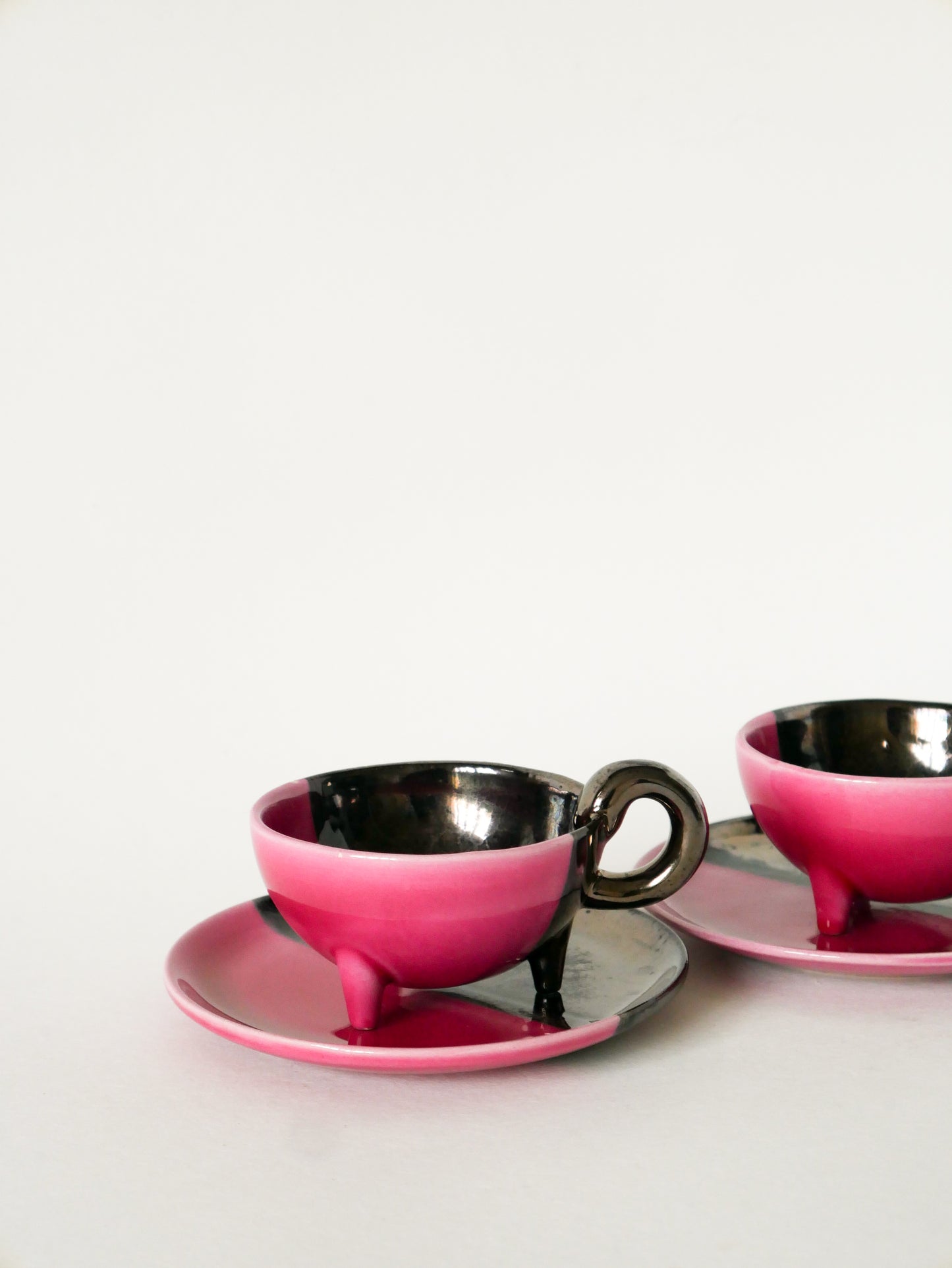 Duo de tasses tripodes et soucoupes Vallauris en céramique bicolore, Rose et Noir Irisé, 1970