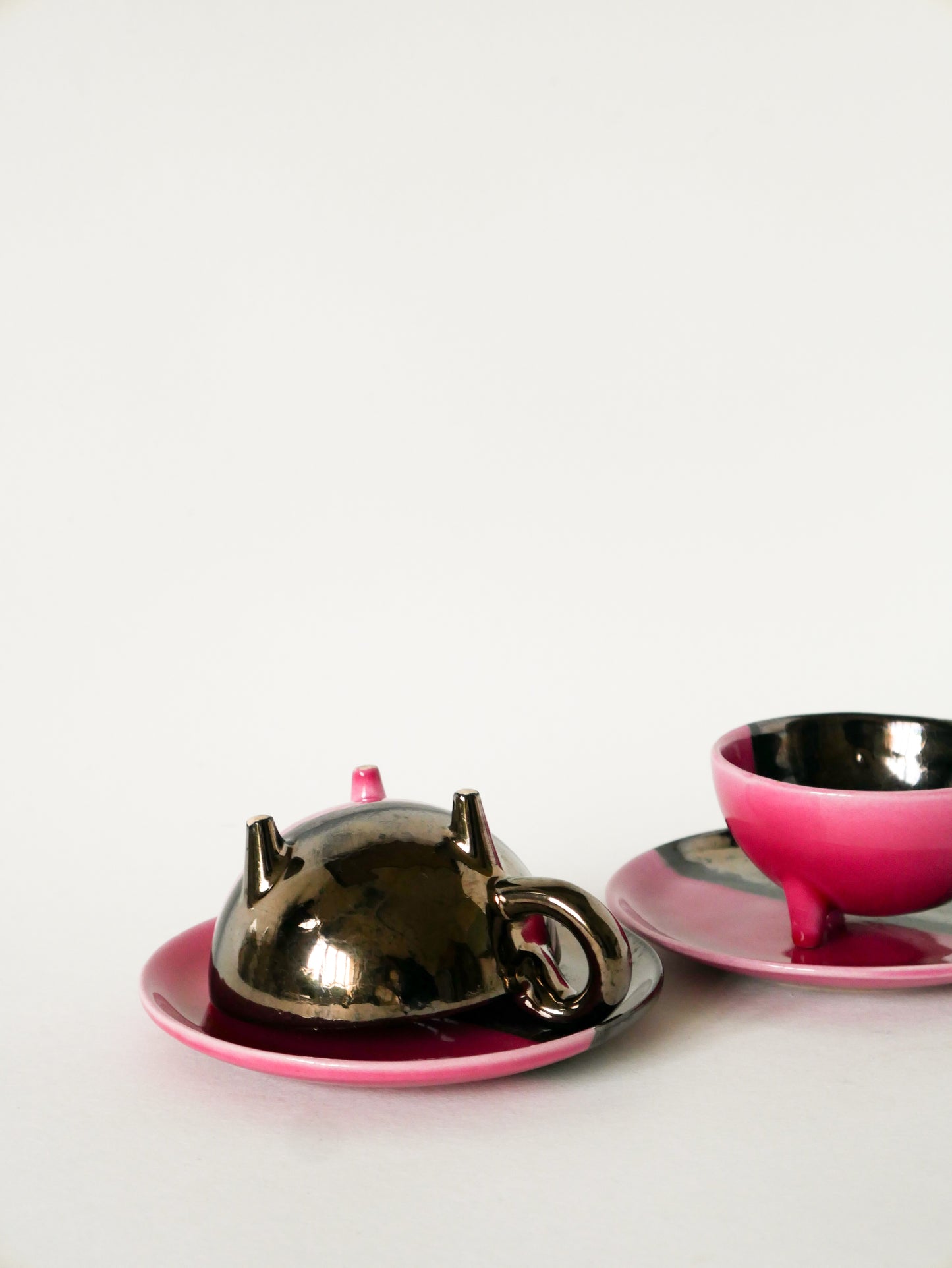 Duo de tasses tripodes et soucoupes Vallauris en céramique bicolore, Rose et Noir Irisé, 1970